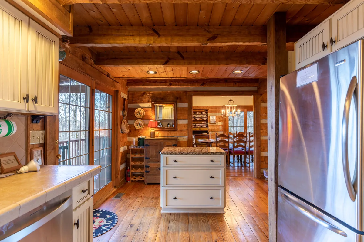 Central island kitchen scene with a stainless steel refrigerator, surrounded by a wooden dining area, creating an open space conducive to cooking, sharing recipes, and celebrating milestones.