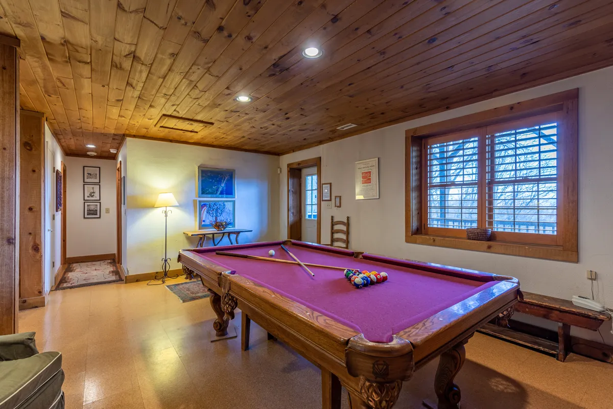 A well-lit recreation space featuring a pool table, windows with scenic views, and warm, inviting decor. The setup suggests both friendly competition and opportunities for socializing in a comfortable setting.